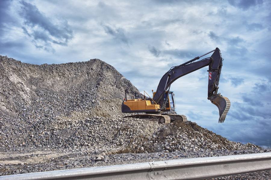 Excavator working a mound of aggregate in a quarry