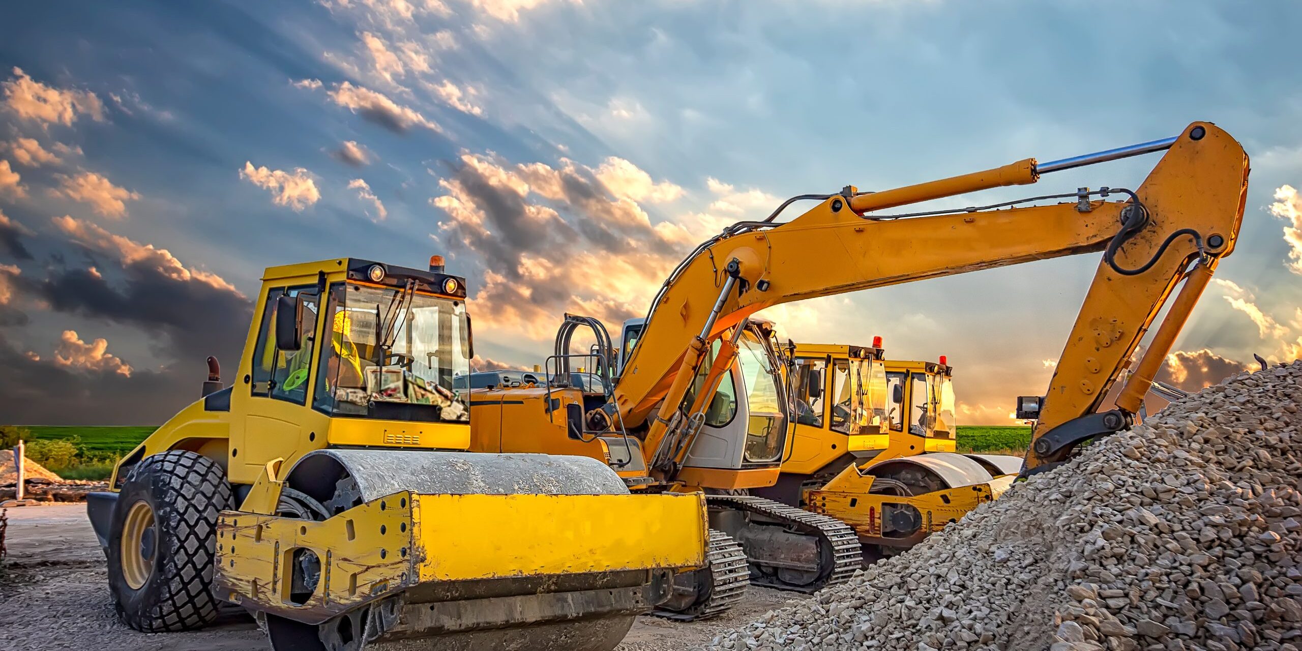 Parked drum roller and excavators at the construction site, after work