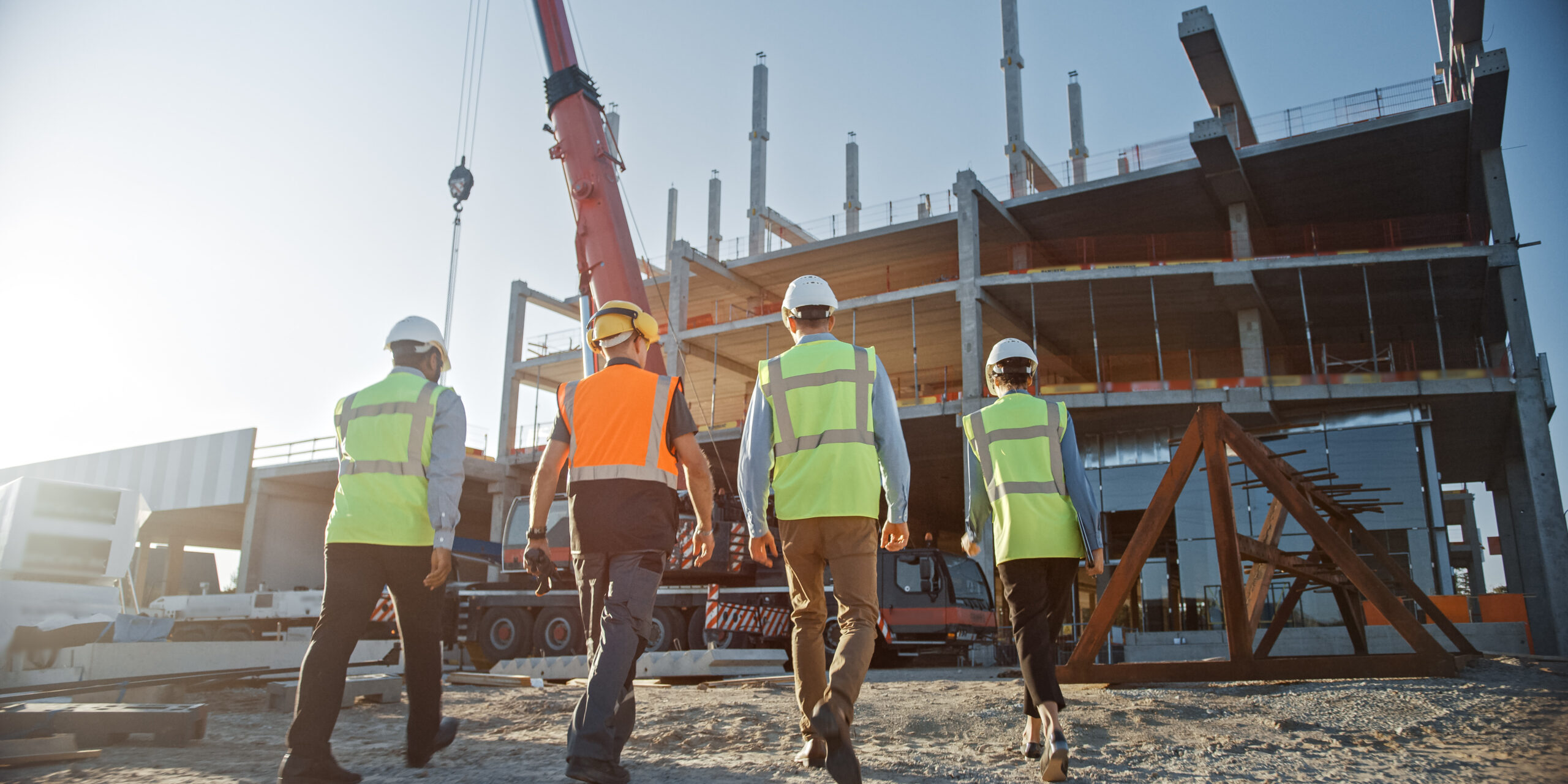 Diverse Team of Specialists Inspect Commercial, Industrial Building Construction Site. Real Estate Project with Civil Engineer, Investor and Worker. In the Background Crane, Skyscraper Formwork Frames